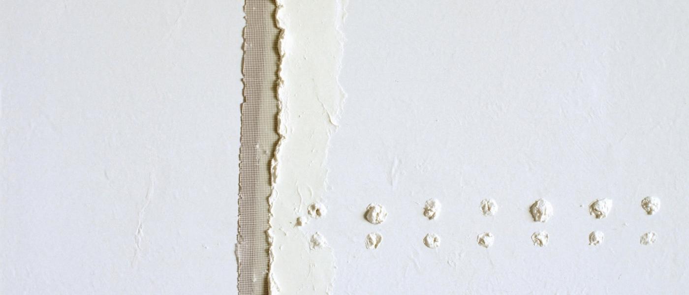 Paper joint tape bedded in white joint compound along a taped drywall seam, feathered smooth on both sides